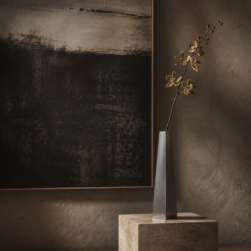 Decorative vase with flowers on a pedestal against a textured wall with abstract art.