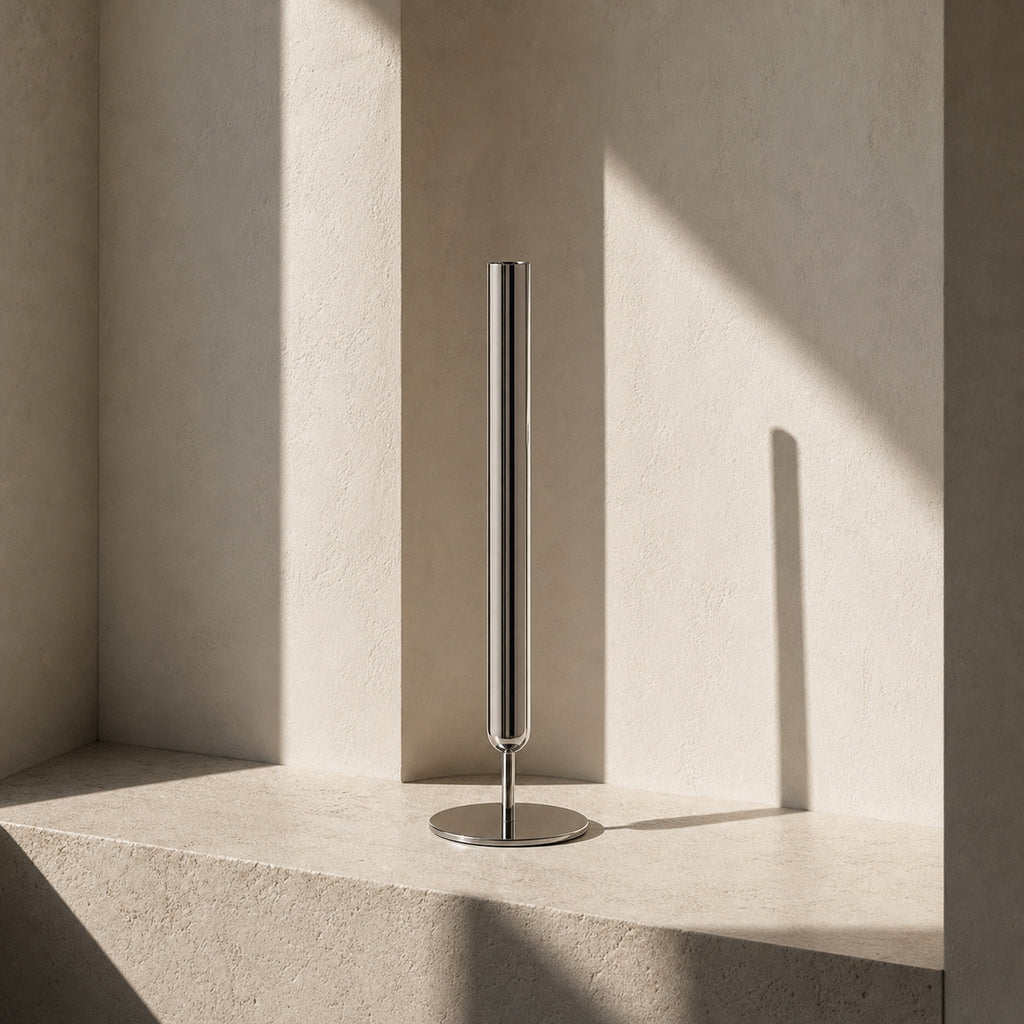 Contemporary silver stem vase, the Lumina Vase Axis, showcasing its pure geometric design without botanicals. The architectural piece is set in a serene, minimalist niche with high-contrast natural lighting and organic stone textures.
