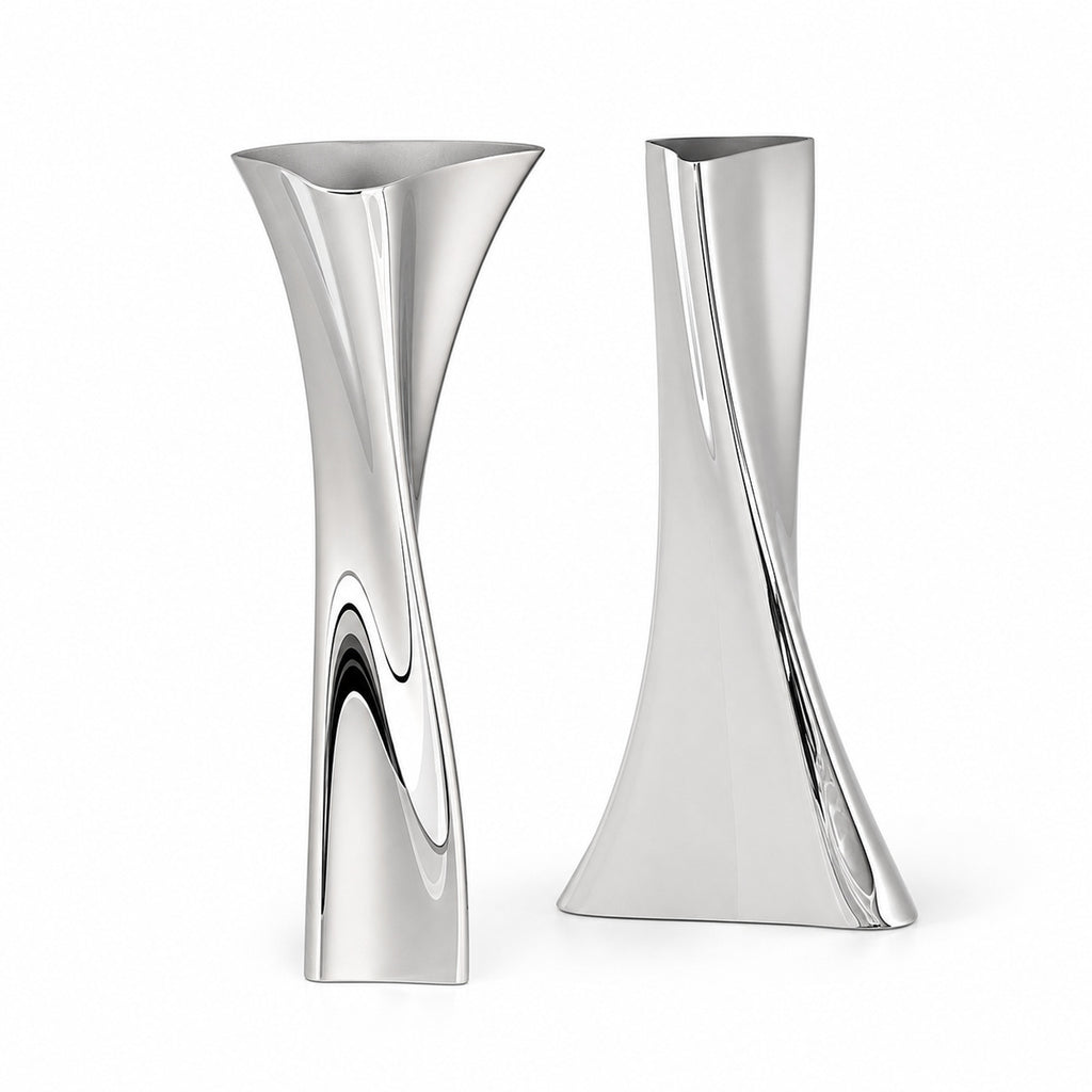 A pair of twisted geometric metallic vases, the Lumina Vase Versa set, highlighting elegant twisted contours, abstract architectural forms, and a highly reflective silver surface. The sculptural set includes two complementary designs: the 'V' model on the left with a flared top, and the 'A' model on the right with a wider base, isolated on a clean white background.