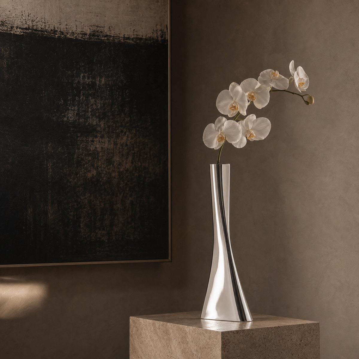 Silver vase with white flowers on a stone surface against a brown wall with abstract art.