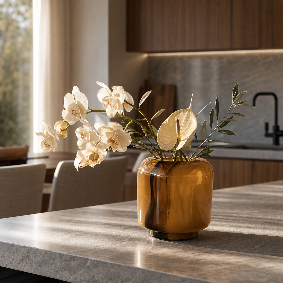 Onda Boleto brown glass vase with white orchids and sculptural foliage on a modern kitchen island